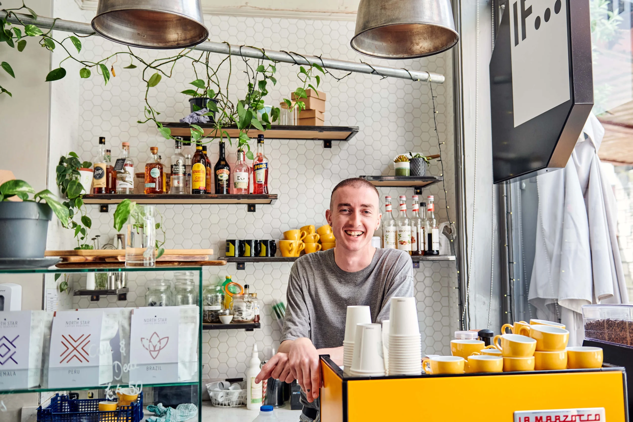A cafe worker poses behind the counter