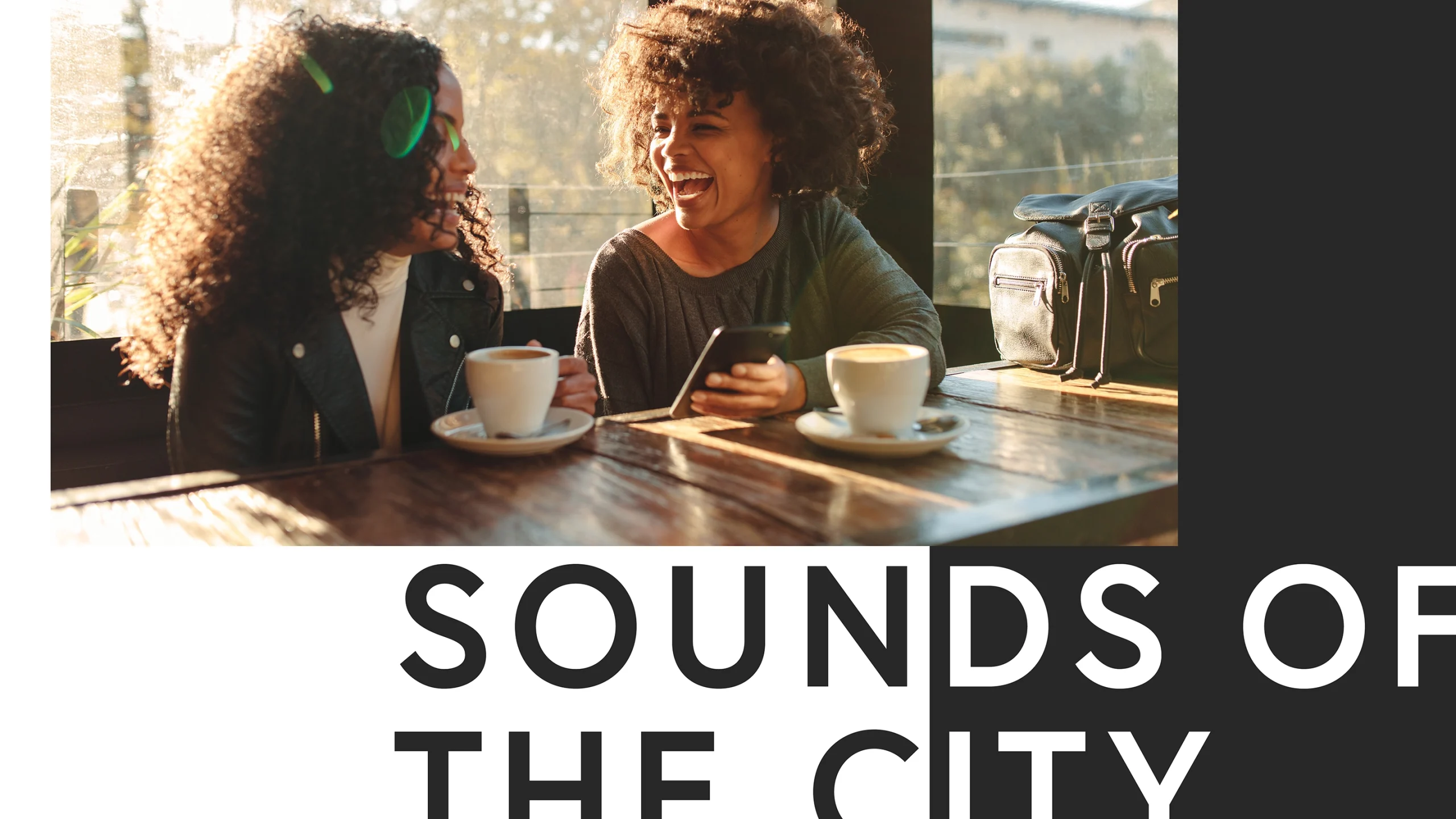 Two women laughing over coffee at a café with the text Sounds of the City emblazoned below