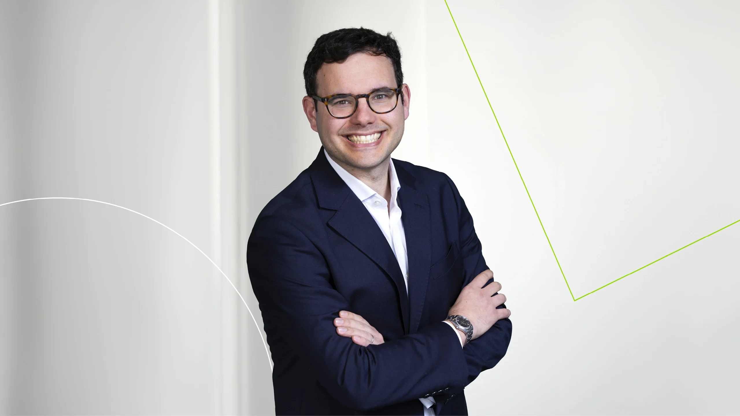 A male J A Kemp employee posing against a white wall with graphic design elements